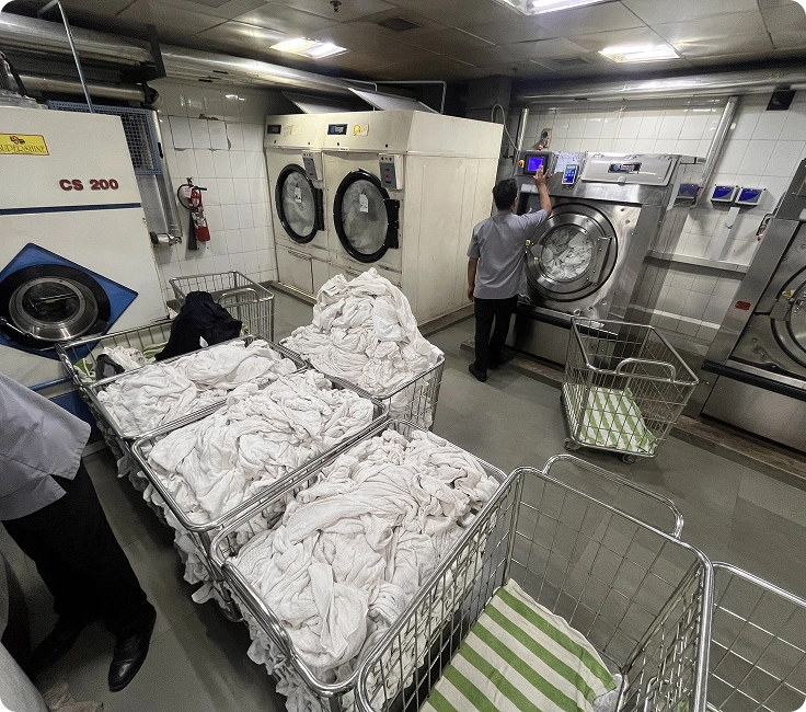 Laundry operator unloading hotel linen from washer extractor at Holiday Inn Aerocity, New Delhi