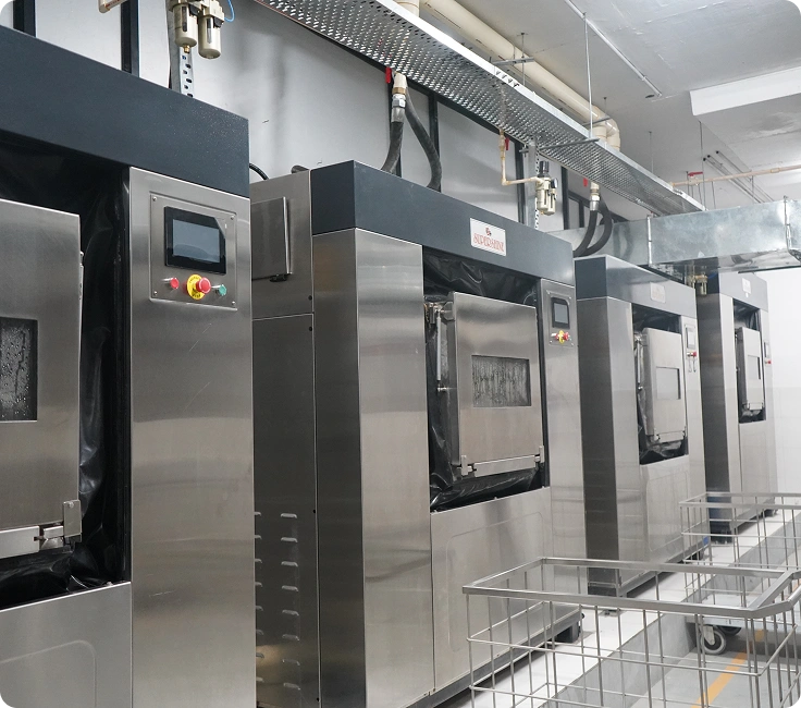Row of stainless steel barrier washer extractors with linen trolleys at Lady Hardinge Medical College and Hospital's laundry facility, New Delhi