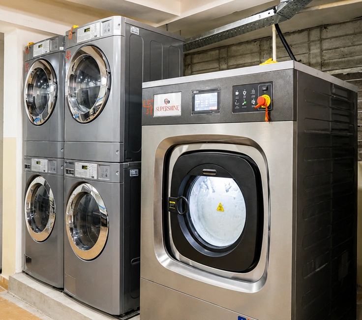 Supershine washer extractor and LG commercial stacked washer dryer units complete laundry room setup at Damodar Dham Nathdwara