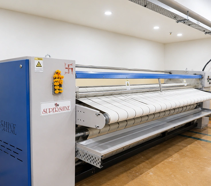 Supershine industrial flatwork ironer side view with blue panel at Damodar Dham guest house laundry room