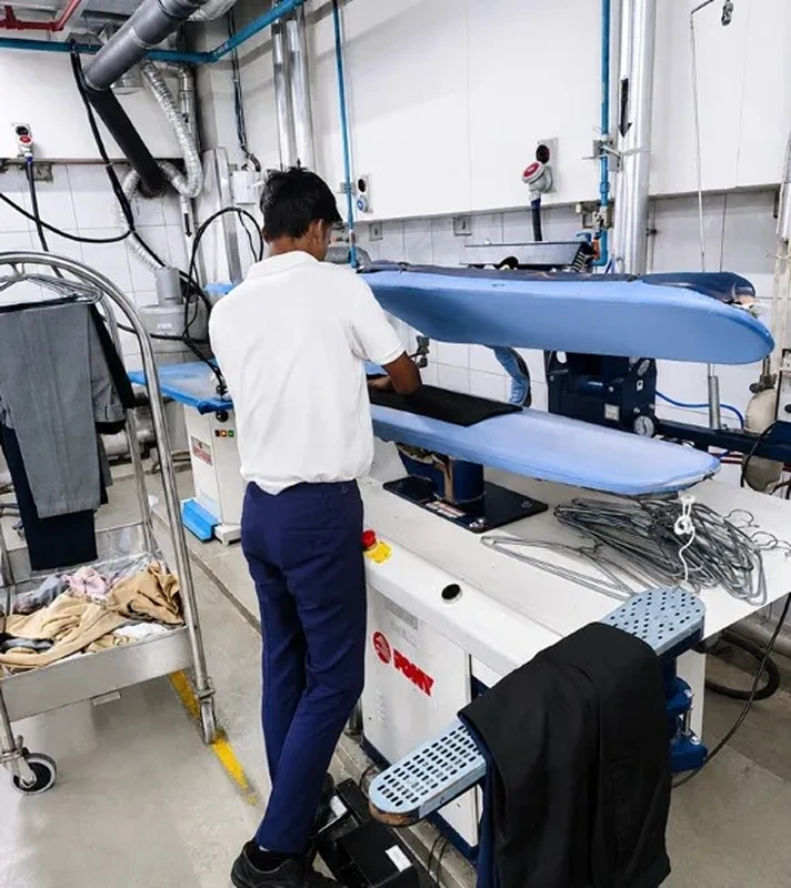 Laundry staff operating Pony trouser press at Taj Palace Mumbai on-premises laundry facility